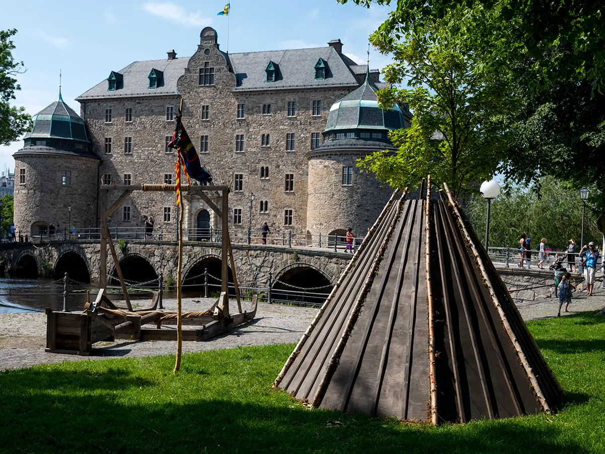 En katapult och en kåta syns i förgrunden, i bakgrunden syns Örebro slott