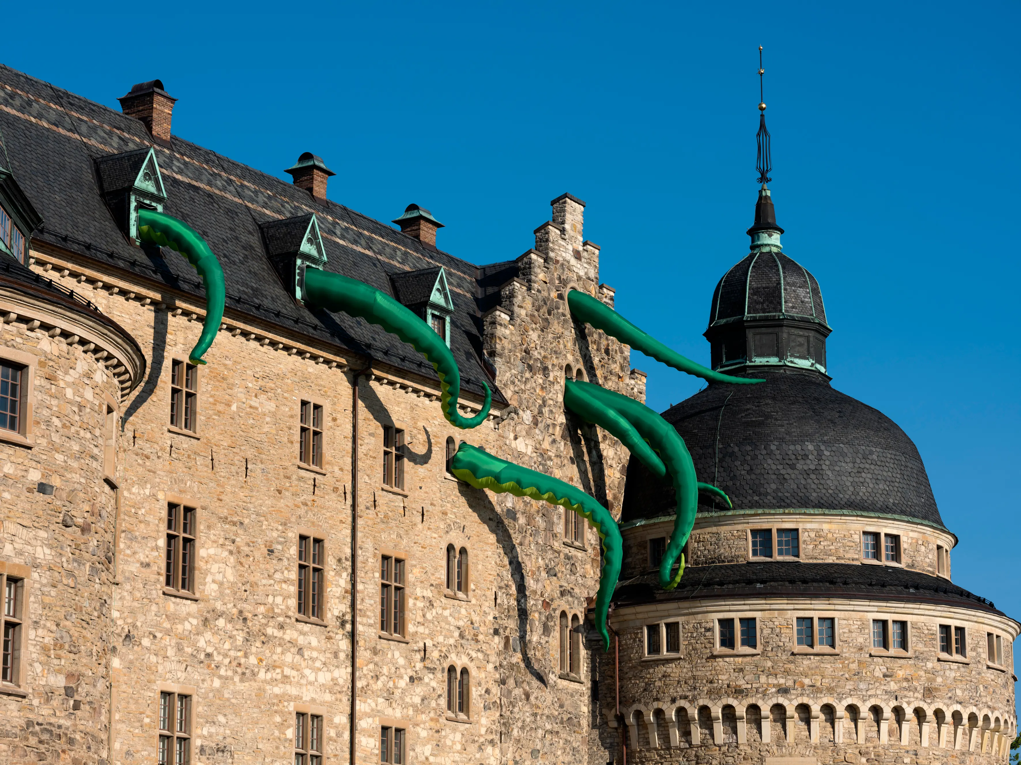 Uppblåsbara gröna tentaklar som sticker ut ur 5 fönster på Örebro slott. 
