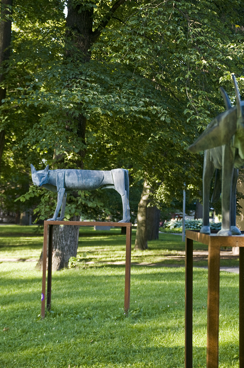 På en gräsmatta står två vargskulpturer upphöjda på en varsin ställning.