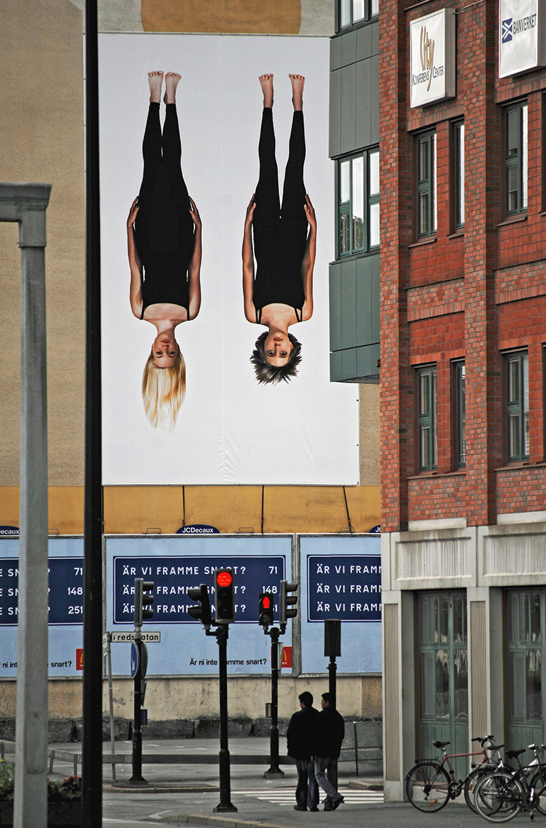På en husfasad hänger en vepa av ett fotografi av två kvinnor upp och ner.