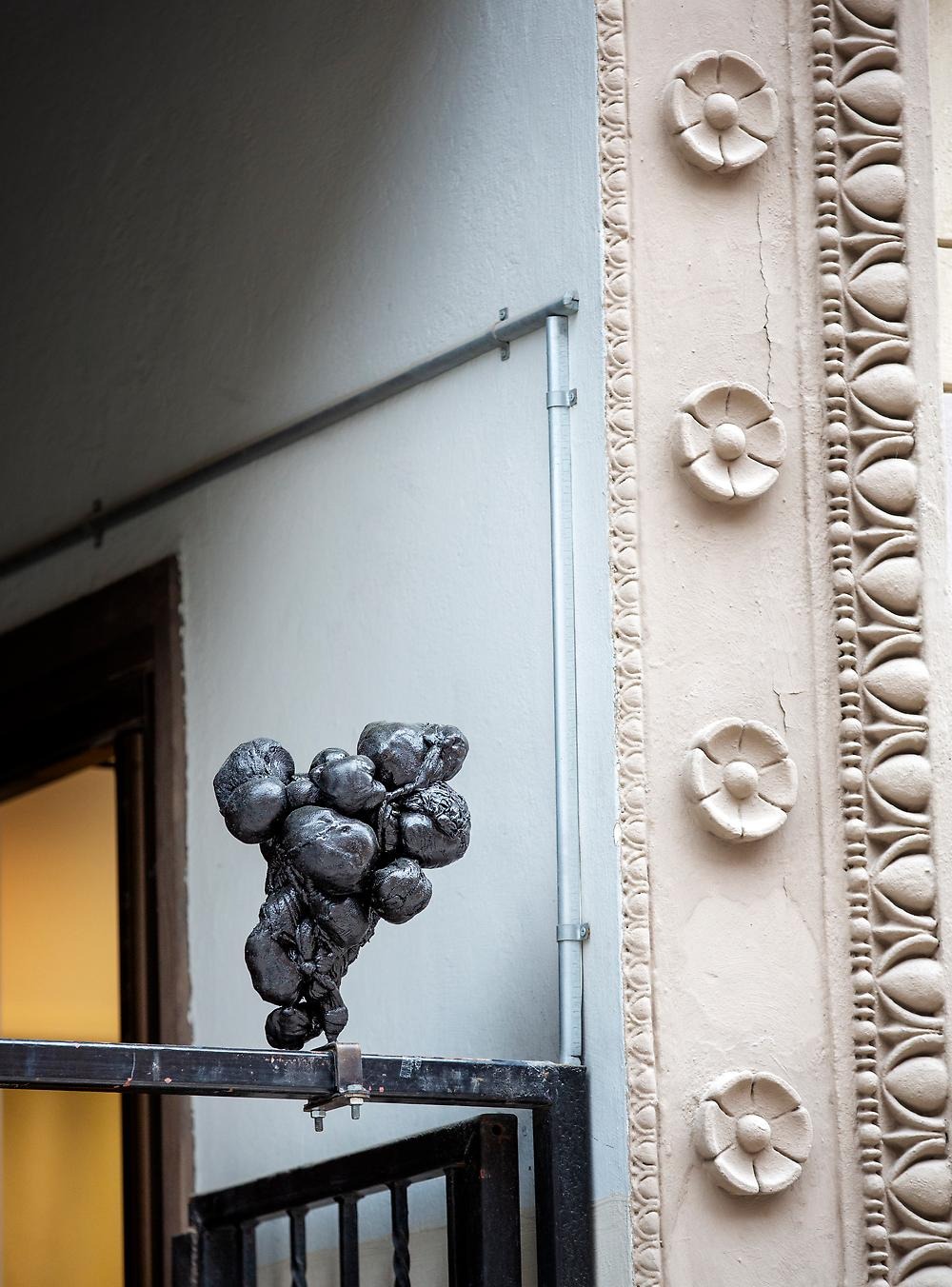 Ett av konstverken som är placerade i stadsrummet på hög höjd, objektet balanserar på en smal metallstång. Konstverket består av hårt sammanknuten svart textil som utgör skulpturen. Skulpturen är mellan 20-30 cm hög.