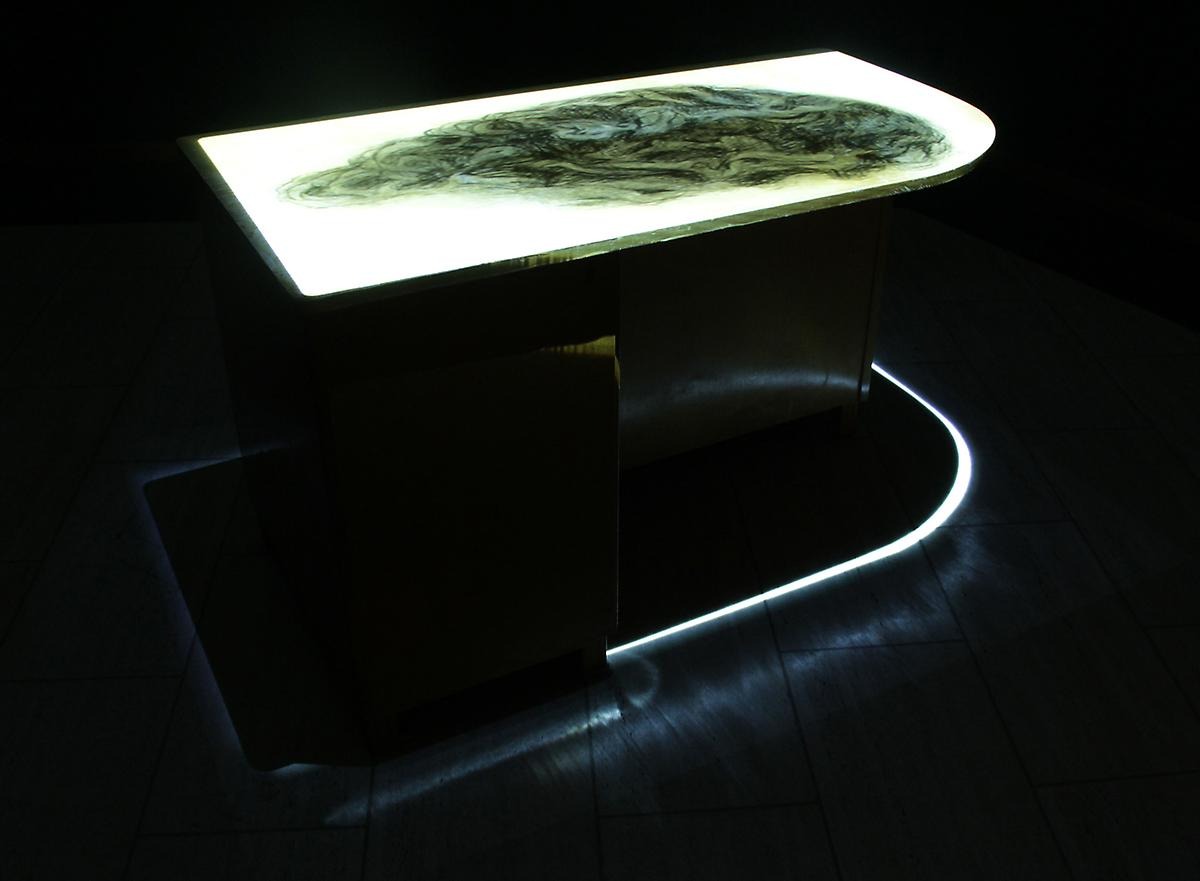 I ett mörkt rum står ett upplyst bord. 