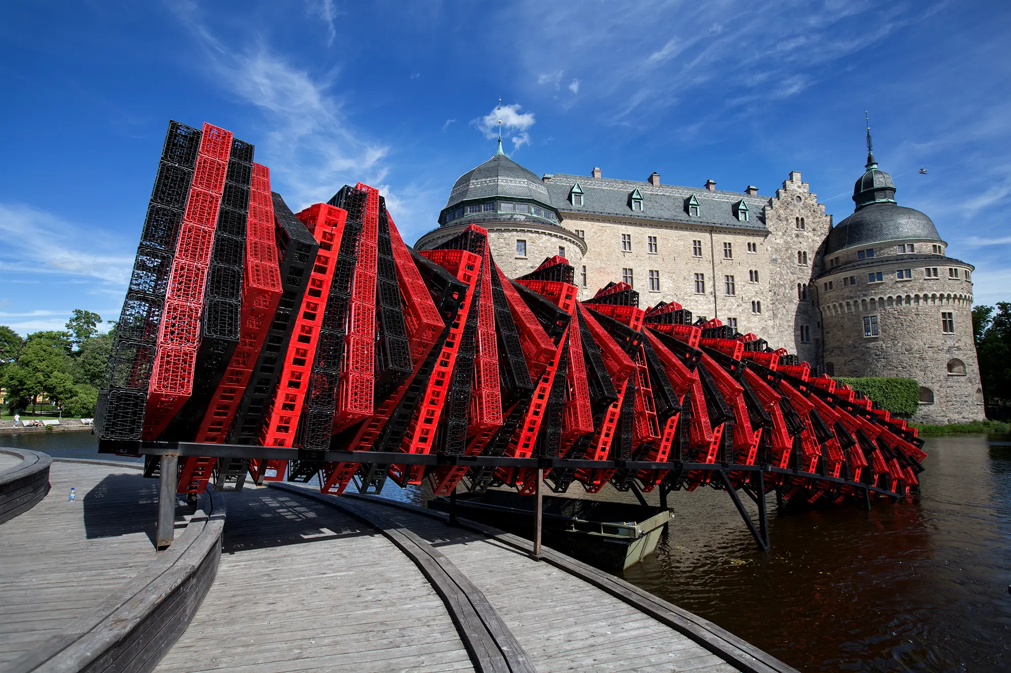 Framför Örebro slott syns en mycket stor skulptur som delvis är placerad över vattnet. Skulpturen består av ett stort antal röda och svarta plastlådor som är ihopsatta i formen av en tät spiral.