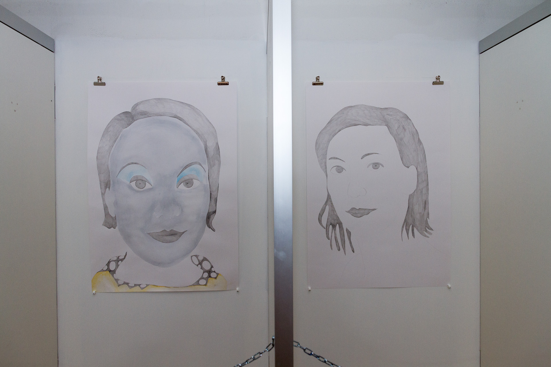 Två vita vägar med två målningar föreställandes två olika kvinnor. 