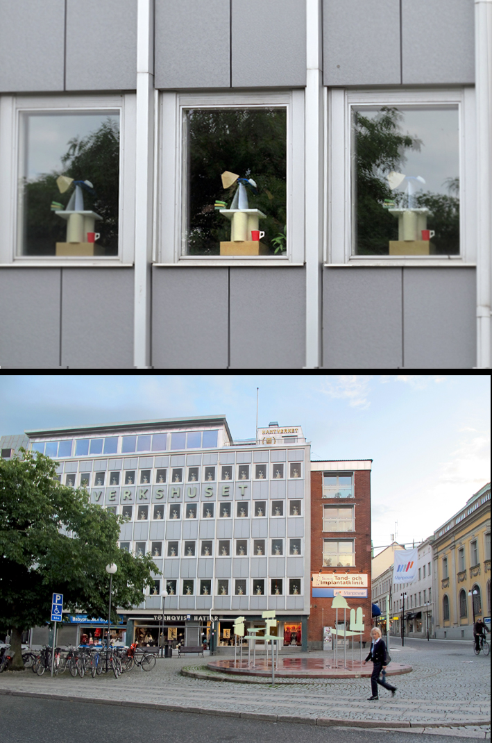 En hel byggnad med många fönster på rad, i varje fönster står likadana konstverk.