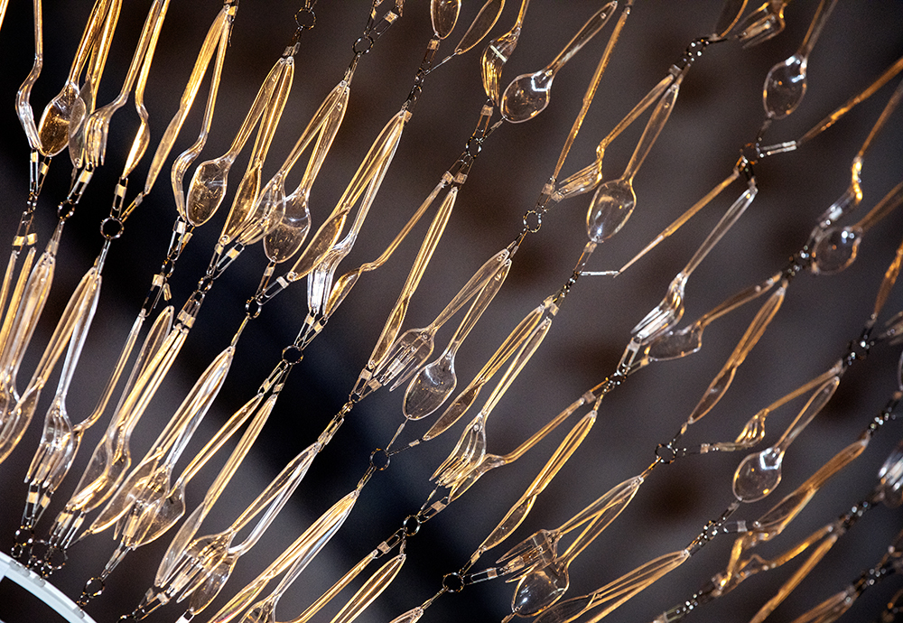Close-up of what makes up the artwork, transparent cutlery that is assembled with small threads and rings to form a pattern.