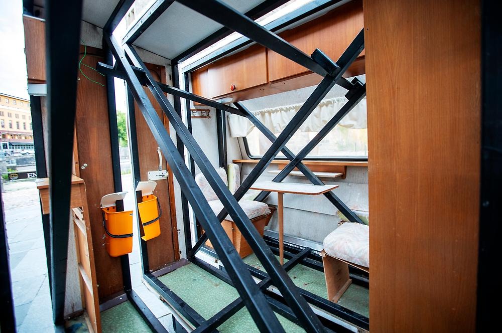 The photo is of the inside of a caravan. You can see the joists, seats and wood paneling.