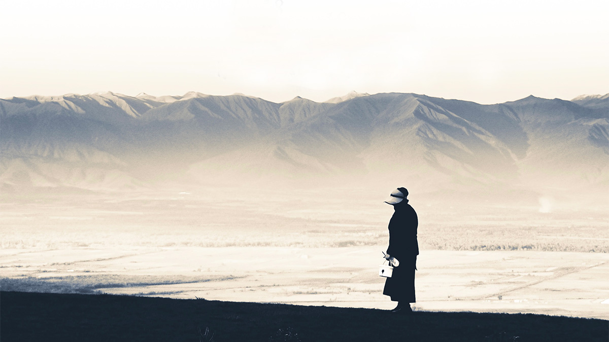 Svartvit bild på en person som står framför en bergskedja
